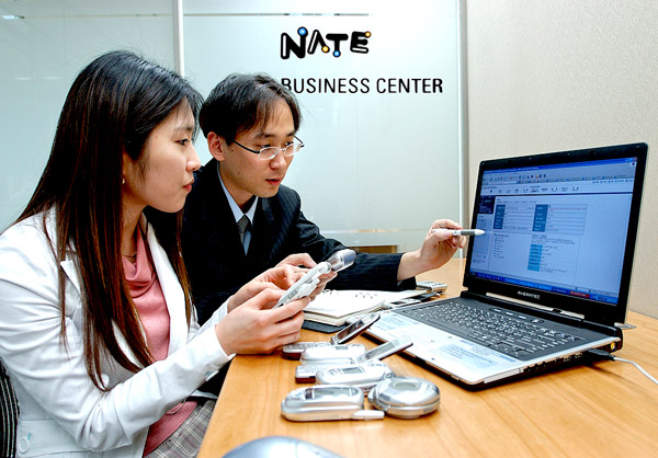 A staff member of an SK Telecom business partner is shown testing a terminal in the NATE Business Center (On April 8th, SK Telecom opened the NATE Business Center. This center is designed to support the tasks of small and medium-sized business partners who are producing and supplying wireless content such as games, music, bell sounds, etc. to SK Telecom. Its size is 40 pyong, and it is located on the 3rd floor of the SK-T Tower that is based in Uljiro, Choong-ku, Seoul).